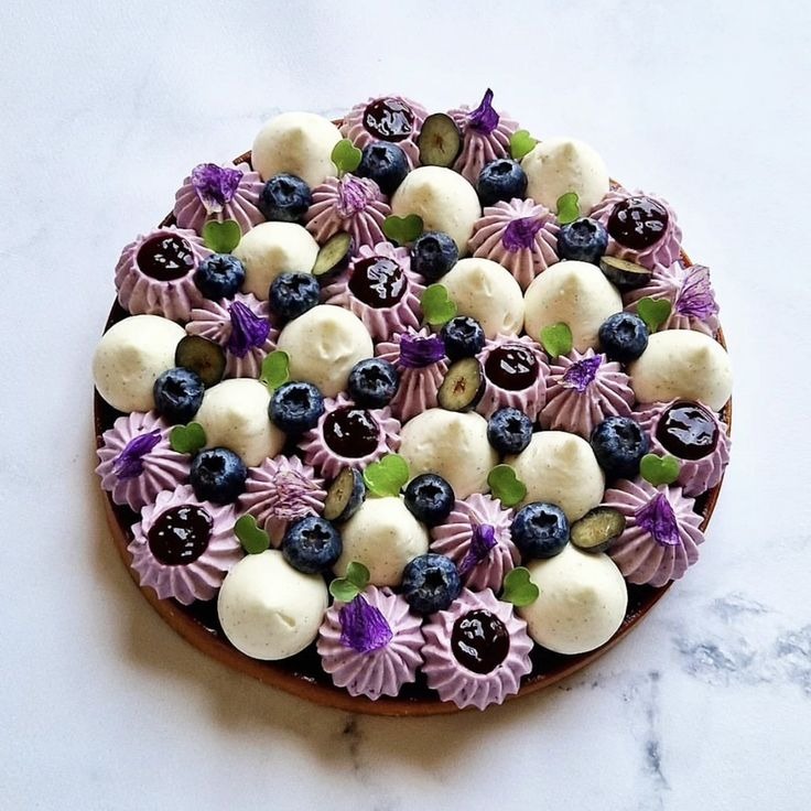 Torta ai mirtilli con ciuffi di crema viola e fiori